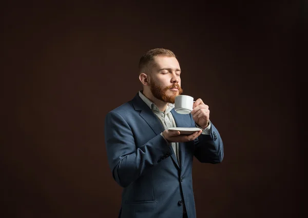 Handsome bearded man enjoying smell of coffee