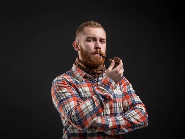Elegant bearded man holding smoking pipe
