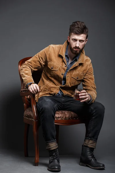 Portrait of serious bearded man with cigar and whisky