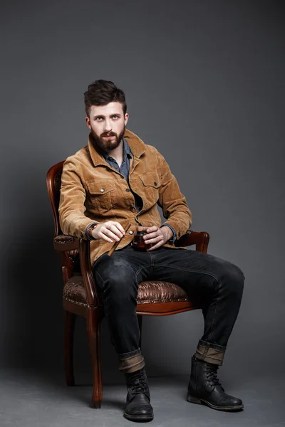 Portrait of serious bearded man with cigar and whisky