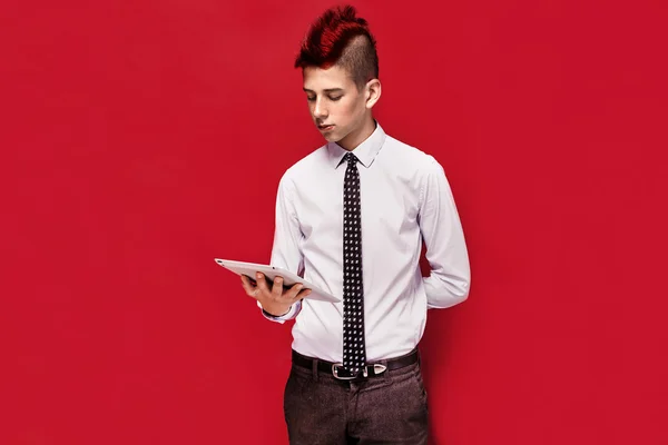 Elegant punk with tablet against of red background