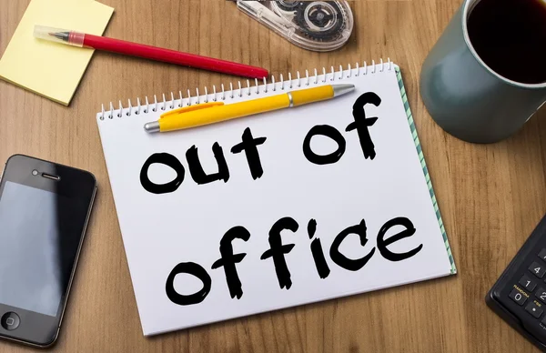 Out of office - Note Pad With Text On Wooden Table