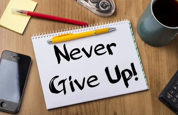 Never Give Up! - Note Pad With Text On Wooden Table