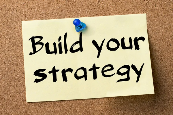 Build your strategy - adhesive label pinned on bulletin board