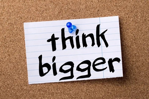 Think Bigger - teared note paper pinned on bulletin board
