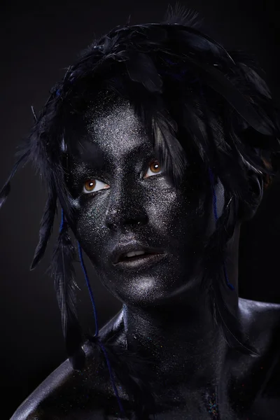 Beautiful woman, black body over dark background, glitters and feathers