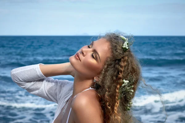 Pretty curly girl portrait with flowers in hear, sea view