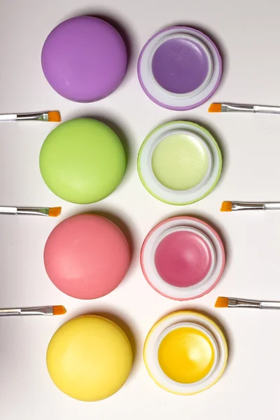 Cosmetic macaroons lying in row, balms, white background, lip brushes