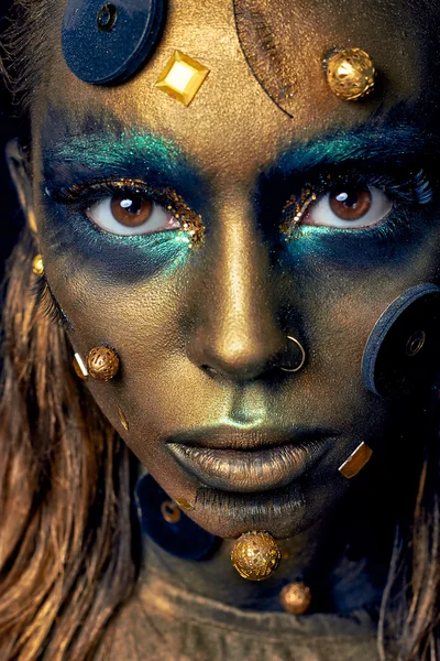 Cosmic unusual makeup with decorative elements on face, golden skin
