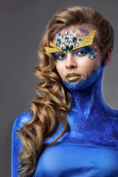 Sensual attractive woman in blue glitter, rhinestones on face, ocean creature, grey background