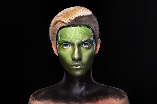 Young girl with creative green and black makeup, face art