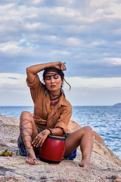 Woman shaman with drum, in mountain sea. Ethnic fashion photoshoot.