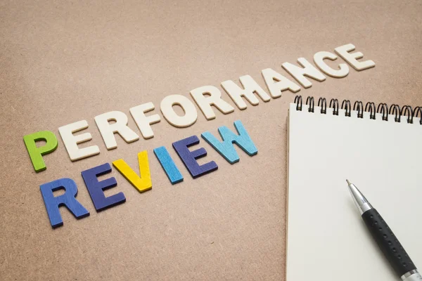 Performance review text with open spiral notebook and pen