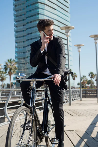 Young businessman in classical bike speaking by telephone