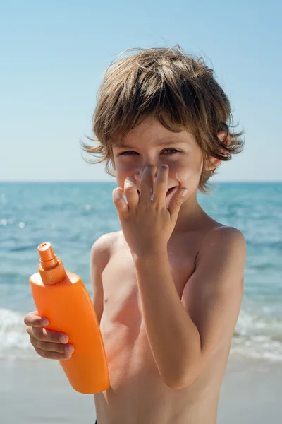 Child apply sun cream on his face with hands