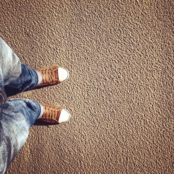 Feet in sneakers on sand