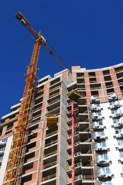 Crane and building construction site against blue sky