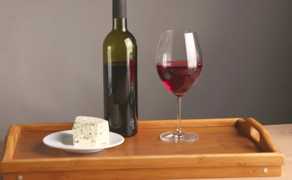 Refined still life of wine, cheese and grapes on wicker tray on wooden table