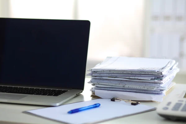 Laptop with stack of folders on table on white background