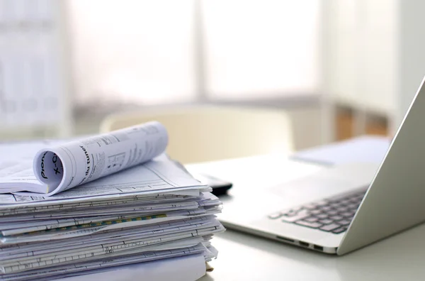 Laptop with stack of folders on table on white background