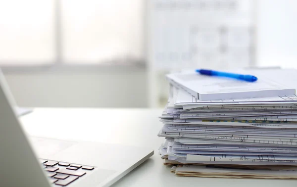 Laptop with stack of folders on table on white background