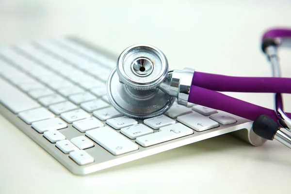 Stethoscope lying on a notebook computer in the background and books