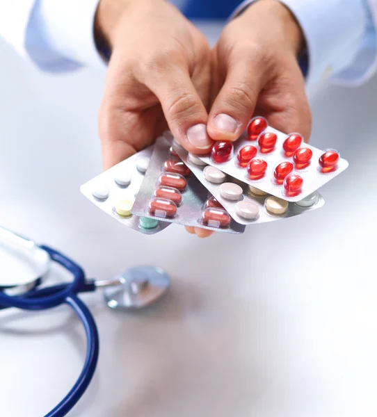 A young doctor holds the patients hand with pills