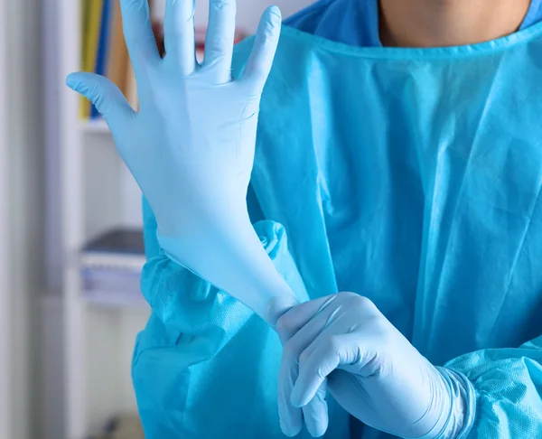 The surgeon wears gloves before surgery. Close-up