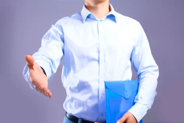 Businessman with papers holds out his hand for a handshake