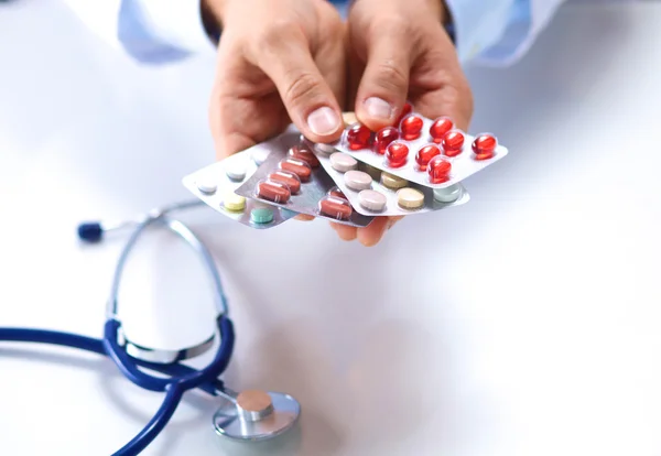 Doctor holds the patients hand with pills