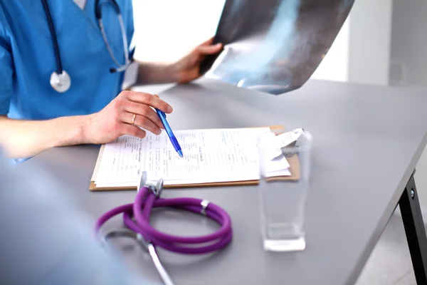 Medical doctor sitting at table and looking patients roentgen