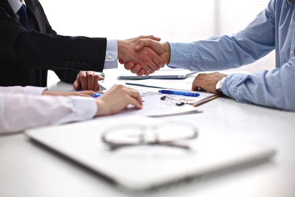 Business meeting at the table shaking hands conclusion of the contract
