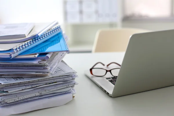 Stack of papers and glasses lying on table desaturated