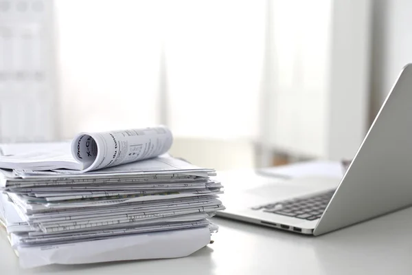 Laptop with stack of folders on table on white background