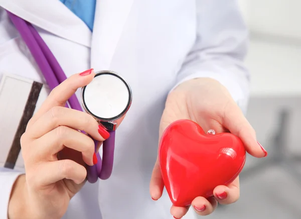 Doctor with stethoscope examining red heart