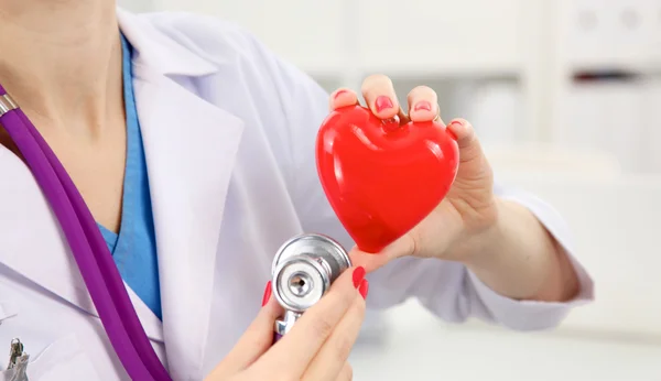 Doctor with stethoscope examining red heart