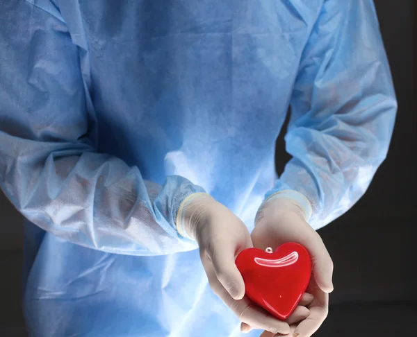 Man surgeon holds a heart in an operating room