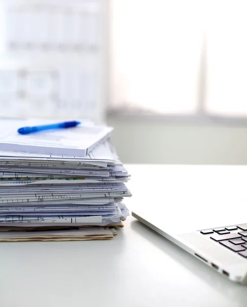 Laptop with stack of folders on table on white background