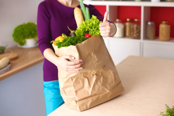 Healthy positive happy woman holding a paper shopping bag full of fruit and vegetables