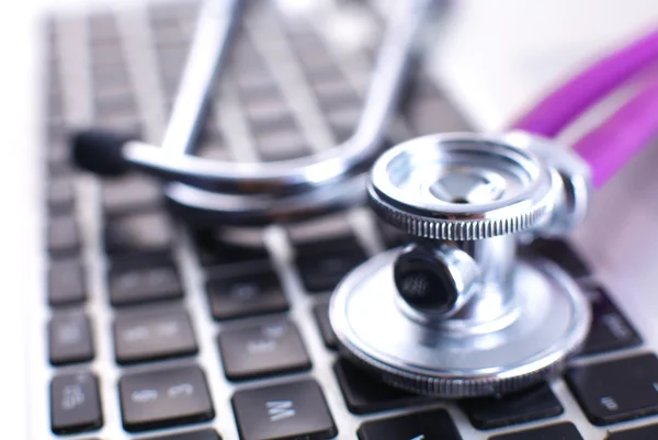 A medical stethoscope near a laptop on a wooden table, on white