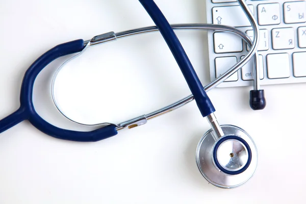 A medical stethoscope near a laptop on table, on white