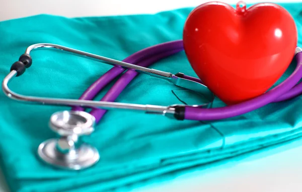 A stethoscope shaping a heart and a clipboard on a medical uniform, closeup