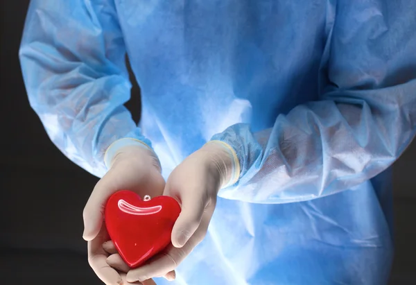 Man surgeon holds a heart in an operating room
