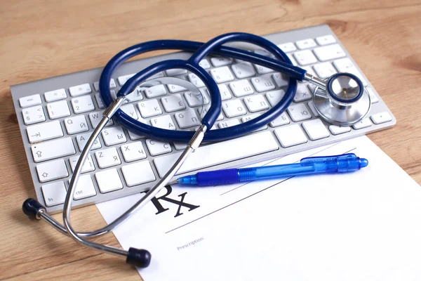 A medical stethoscope near a laptop on a wooden table