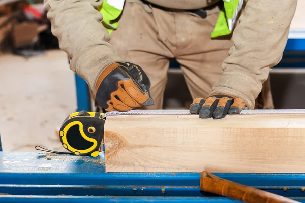 Building a wall for frame house. Worker make marks for cutting timber