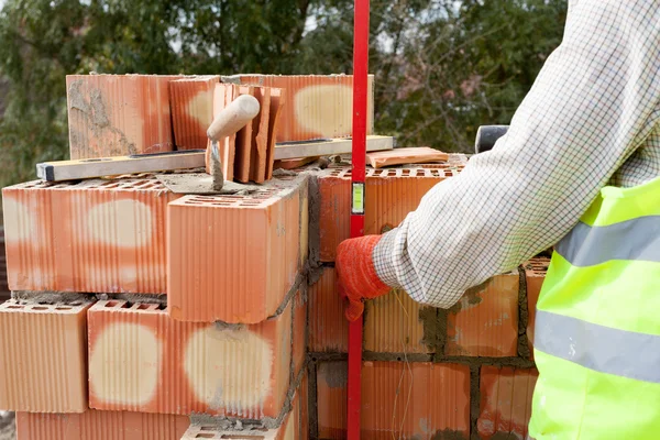 Construction mason worker measuring with professional level the bricks on walls