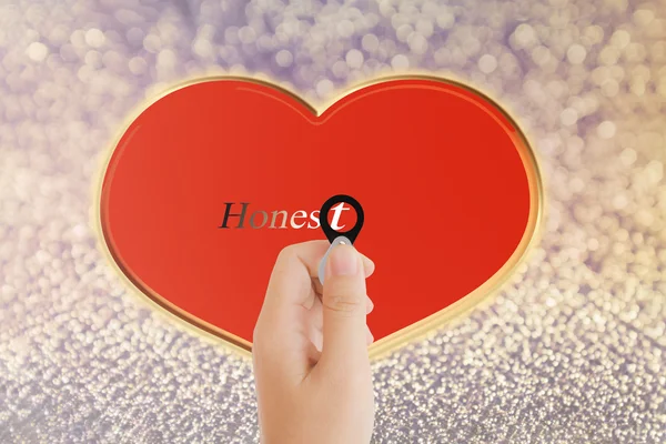 Isolated hand with lens and text honest with red heart shape on