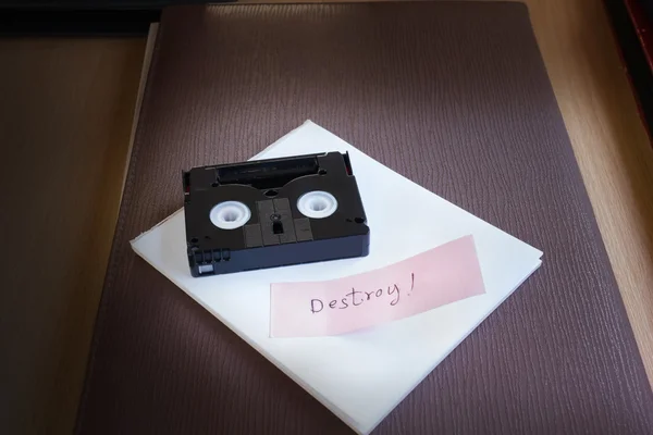 Mini DV cassette tape on note text word destroy in dim light roo