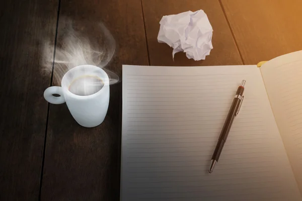 White cup of black coffee with blank paper note and pencil on wood table, good coffee good idea with blank or empty paper