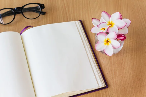 Plumeria or frangipani flowers in glass with blank note book